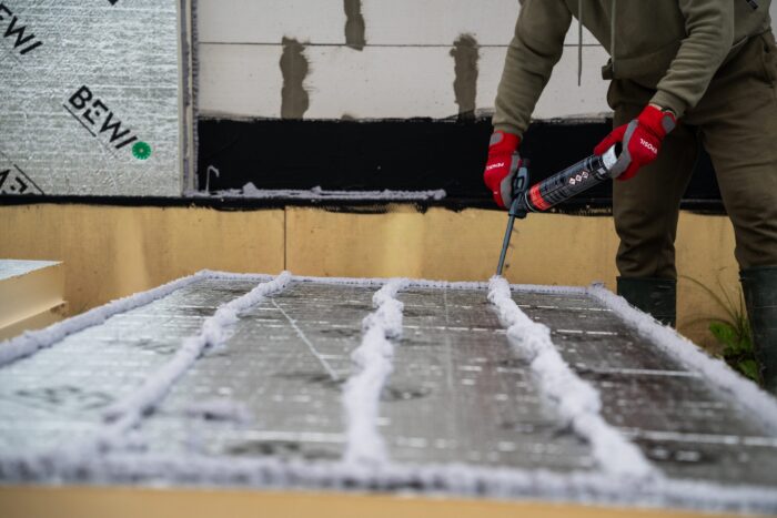 Man applying foam adhesive to insulation panels