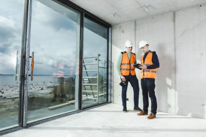 pracownicy budowlani sprawdzający montaż okna w trakcie prac budowlanych